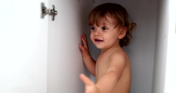 Cute child boy inside closet cabinet. Infant kid hides inside closet, closing door - Πλάνα, βίντεο