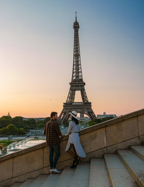 Eiffel tower at Sunrise in Paris France, a Young couple in a city trip by Eiffel tower at Sunrise, man woman in love, valentine concept in Paris the city of love - Zdjęcie, obraz