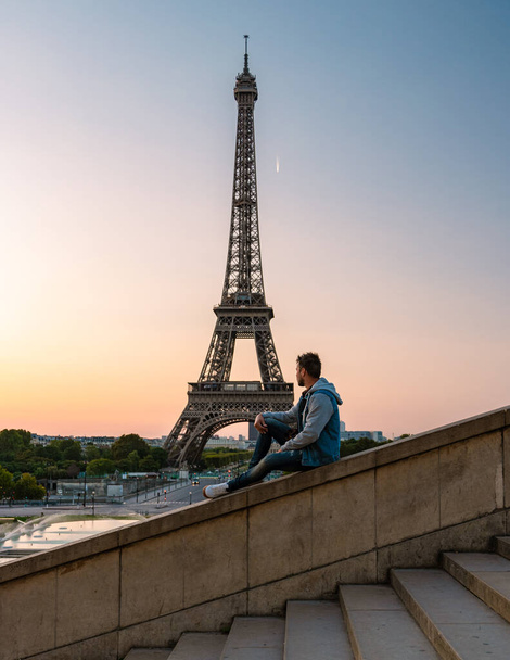 Young men watching sunrise by the Eiffel tower, Eiffel tower at Sunrise in Paris France, Paris Eifel tower on a summer day in the city of Paris France - Photo, image