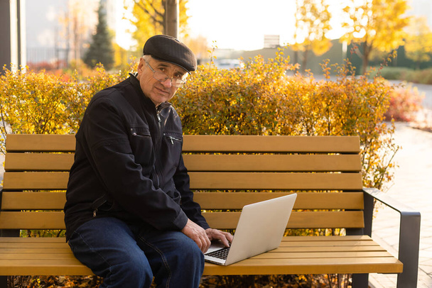 літній чоловік з ноутбуком в осінньому парку
 - Фото, зображення