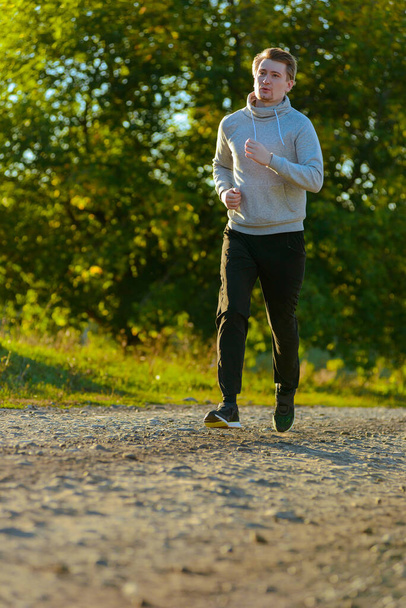 Running man jogging in rural nature at beautiful summer day. Sport fitness model caucasian ethnicity training outdoor. - Foto, Imagen