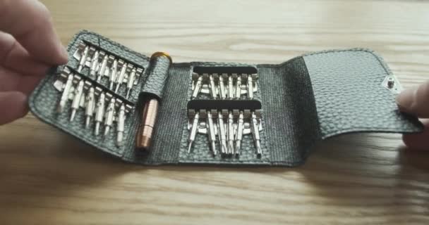 male hands close a set of mini screwdrivers with bits lying on the table in a leather case. The concept of finishing work. First-person view. High quality 4k footage - Video