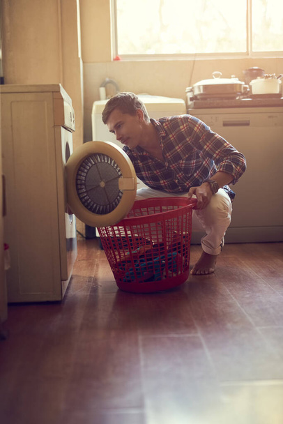 Mastering the art of laundry. a young man doing laundry at home - 写真・画像