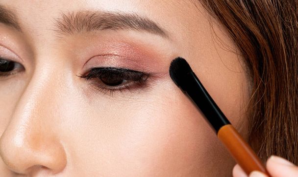 Closeup ardent young woman with healthy fair skin applying her eyeshadow with brush. Female model with fashion makeup. Beauty and makeup concept. - Foto, immagini
