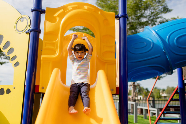 Little girl child going down the slide outdoors at the park or playground - Valokuva, kuva