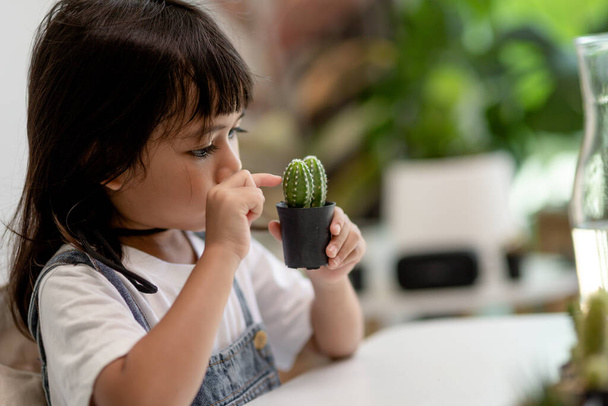 Kid gently touches the new stem of the cactus he grows with care nature education, Montessori, and observation skills concepts. - Fotó, kép