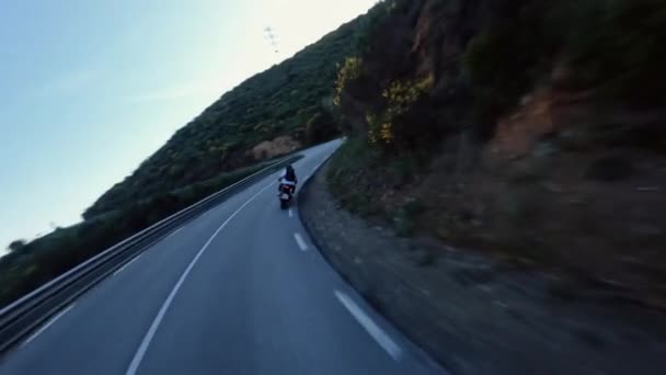 Fast motorcycle riding on serpentine road during golden hour, driver with white long sleeve shirt . followed with high speed fpv drone, Slowmo 4k footage - Materiaali, video
