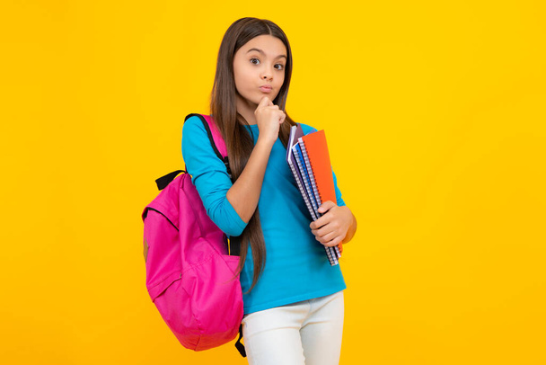 Back to school. Teenager schoolgirl hold book and copybook ready to learn. School children on isolated yellow studio background. Thinking face, thoughtful emotions of teenager girl - Fotoğraf, Görsel