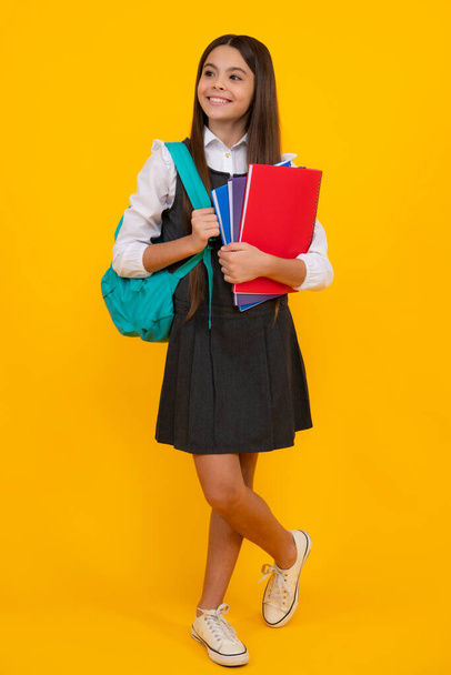 School girl teenager child with book and copybook. Teenager schoolgirl student with backpack, isolated background. Learning and knowledge education concept - Foto, imagen