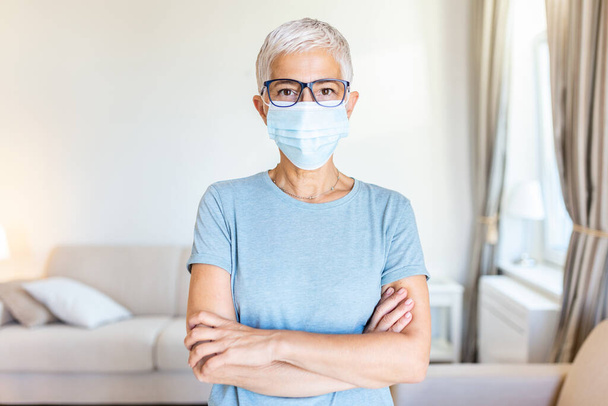 Senior woman in respiratory mask. Masked woman looks at camera. Cold, flu, virus, tonsillitis, respiratory disease, quarantine, epidemic concept. - Photo, Image