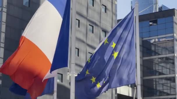 Франция и флаг ЕС на флагштоке отличного качества. Французская Республика и Европейский Союз размахивают флагом на фоне ветра здания стеклянный небоскреб в Париже. Высококачественные 4k кадры - Кадры, видео