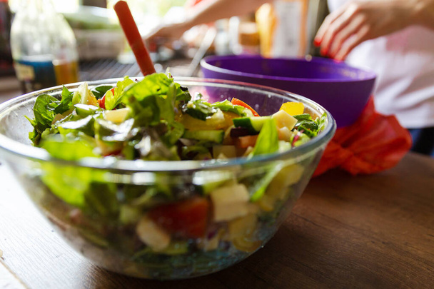 Прозрачная миска свежего зеленого салата закрывается на кухонном фоне стола. Концепция полезной и простой еды - Фото, изображение