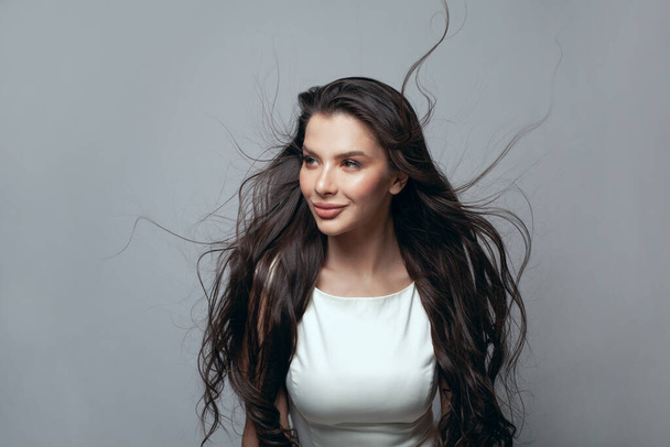 Veselá žena brunetka s dlouhými tmavohnědými vlasy na bílém pozadí - Fotografie, Obrázek