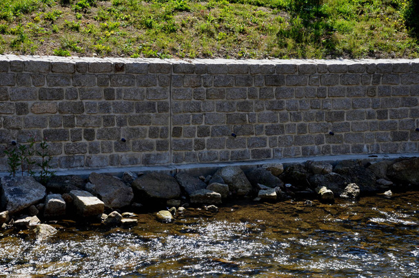 restoration of the retaining wall directly above the mountain stream. stones. the water-soaked wall needed to be repaired and the joints filled with cement mortar. mountain stream with round stones - Photo, Image