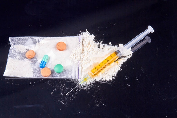 Close-up pile of various drugs and syringe on black background. Drug use and addiction concept. - Photo, image
