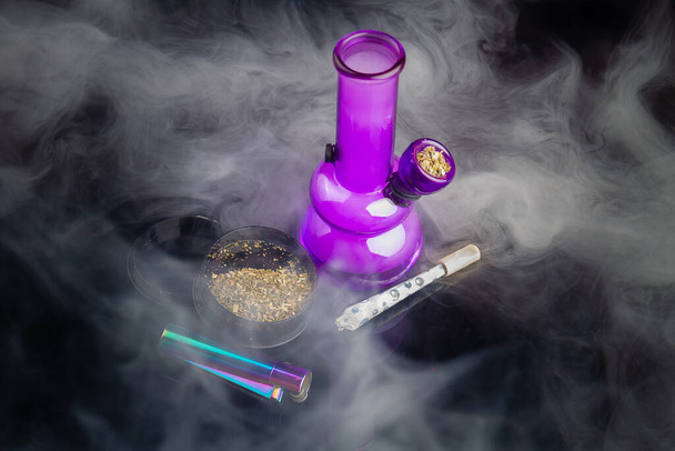 Purple glass bong with joint and a lot of thick white smoke. Top view marijuana weed addiction concept. - Foto, Imagem