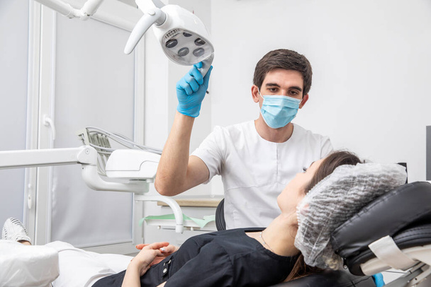 Hammaslääkäri säätää hammaslääkärin lamppua hammashoitolassa - Valokuva, kuva