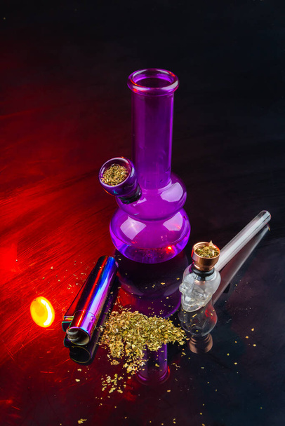 Вертикальный кальян и трубка, наполненная травой. Комплект принадлежностей для курения марихуаны. - Фото, изображение