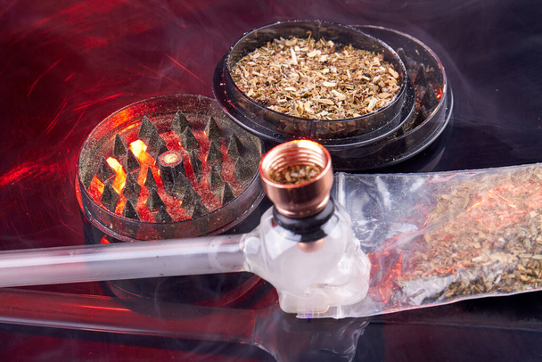 Glass smoking pipe with round grinder filled with weed. Tools for smoking close-up. - Fotó, kép