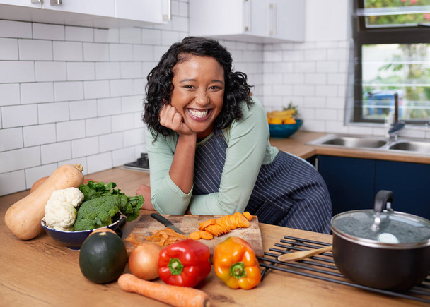 A young multiracial woman poses happily with her dinner progress in the kitchen. High quality photo - Foto, afbeelding