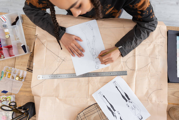 Top view of african american craftswoman drawing sketch on sewing print in workshop  - Fotografie, Obrázek