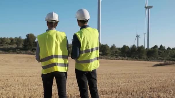 Team of engineers working in a wind turbine farm. Sustainable lifestyles, renewable energy and technology concept. - Video