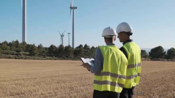Два інженери перевіряють систему вітрових турбін, працюючи на вітроелектростанції. Сталий спосіб життя, концепція відновлюваної енергетики та технологій
. - Кадри, відео