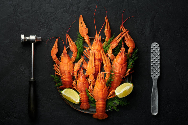 Boiled Crayfish on black plate on dark slate table top. Red crawfish with green dill and lime is popular party dish. Top view - Foto, Imagen