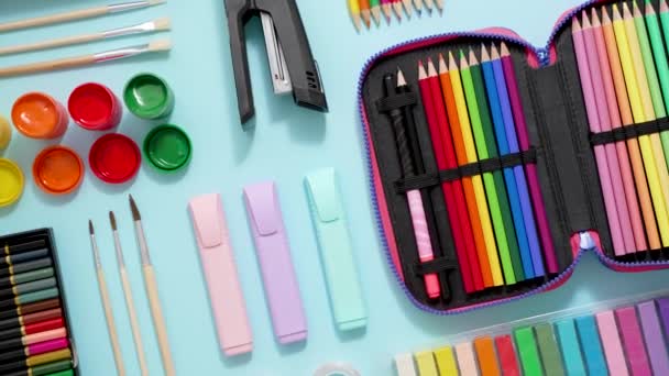 Back to school concept. Colorful school supplies placed on blue background. Top view, flat lay - Imágenes, Vídeo