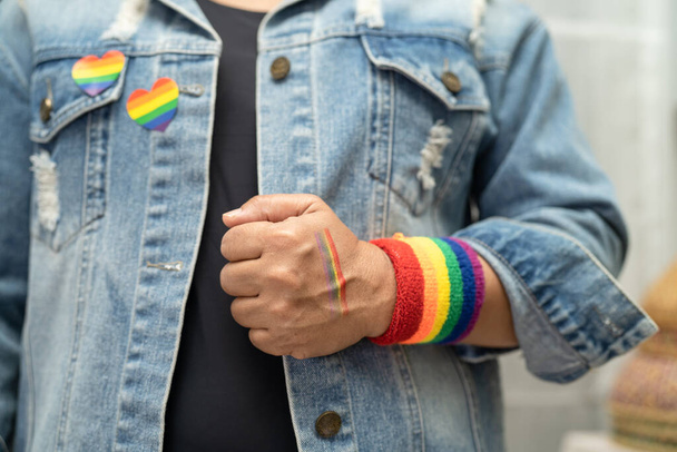 Asian lady wearing rainbow flag wristbands, symbol of LGBT pride month celebrate annual in June social of gay, lesbian, bisexual, transgender, human rights. - Photo, Image
