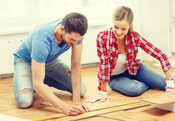 smiling couple measuring wood flooring - Фото, зображення