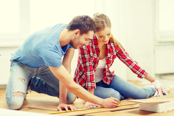 smiling couple measuring wood flooring - Foto, immagini