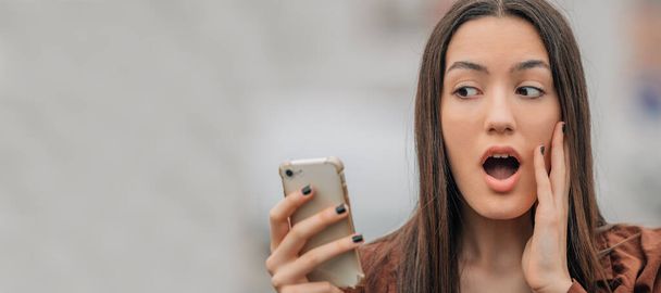 surprised girl looking at mobile phone or smartphone - Foto, imagen