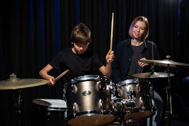 Young woman teaching boy to play drums - Foto, imagen