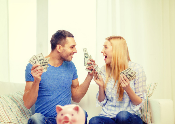Casal com dinheiro e mesa de ot piggybank em casa
 - Foto, Imagem