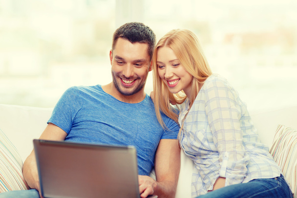 χαμογελαστό ευτυχισμένο ζευγάρι με φορητό υπολογιστή στο σπίτι - Φωτογραφία, εικόνα