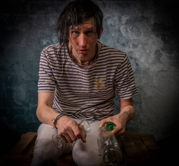 Dirty black hair man with alcohol glasses and bottles and old stone dark wall - Photo, Image