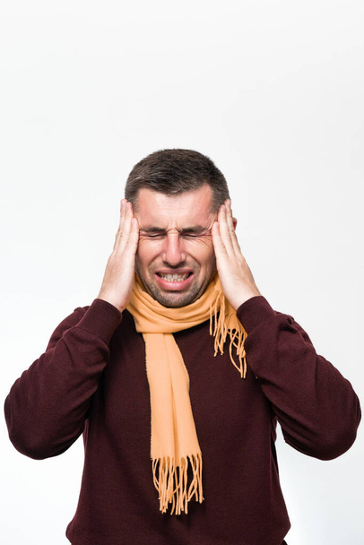 A man holds his hand on his head because of a headache, a portrait of a man on a white background, a man's neck is wrapped in a scarf. - Foto, Bild