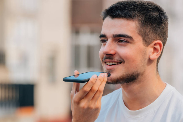 young man with mobile phone sending voice message - Fotografie, Obrázek