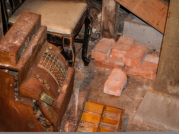 Rusty abandoned cash register amongst stored junk and bricks under Seattle city. - Foto, Bild