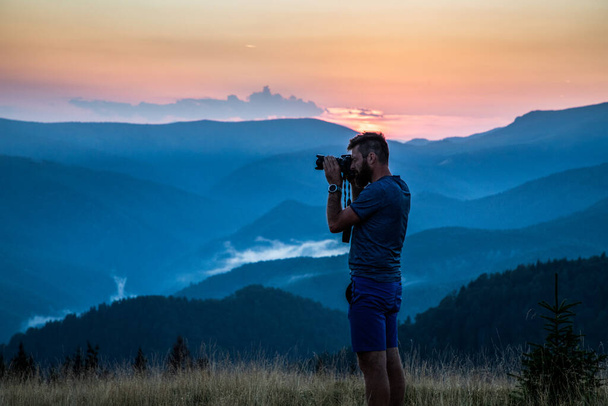 man taking photos of sunset in mountains - Photo, image