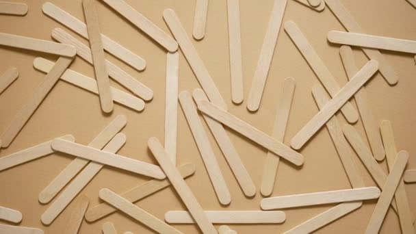 Wooden popsicle sticks, scattered on top of a beige background. Flat lay - Video