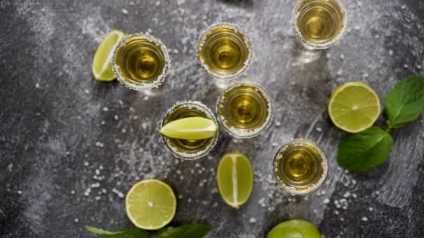 Top view of Golden Tequila shots served with lime and sea salt on table, flat lay. - Video