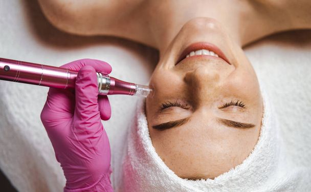 Top view of freckled woman getting hardware cosmetology treatment at spa. Dermatology, cosmetology. Girl facial treatment. Skin care. - Photo, image
