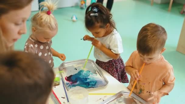 Multi-cultural nursery school. Toddlers playing with striped straws and milk painting, using nontoxic food coloring for colors. Creative kids activity for using their senses and brain development - Video