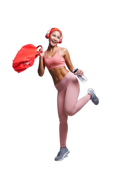 Happy Asian athlete woman in fitness outfit wearing headphone and holding bag posing like enjoy. Lifestyle sport workout girl. - Фото, зображення