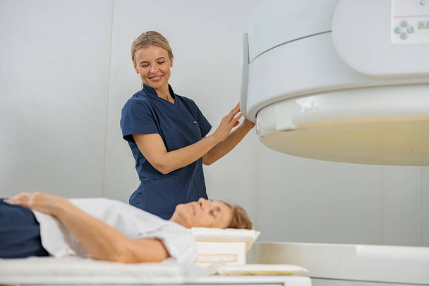 Ακτινολόγος ελέγχει MRI ή αξονική τομογραφία με ασθενή που υποβάλλεται σε διαδικασία. Ιατρικός εξοπλισμός υψηλής τεχνολογίας - Φωτογραφία, εικόνα