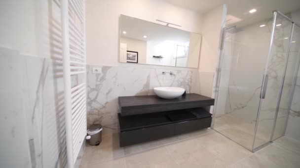 Tágas fürdőszoba szürke tónusú, fűtött padlóval, zuhanyzó és mosogató hiúság. Modern fürdőszoba belső. - Felvétel, videó