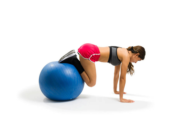 Active latin woman making a plank using a stability ball and exercising over a white background - Fotó, kép