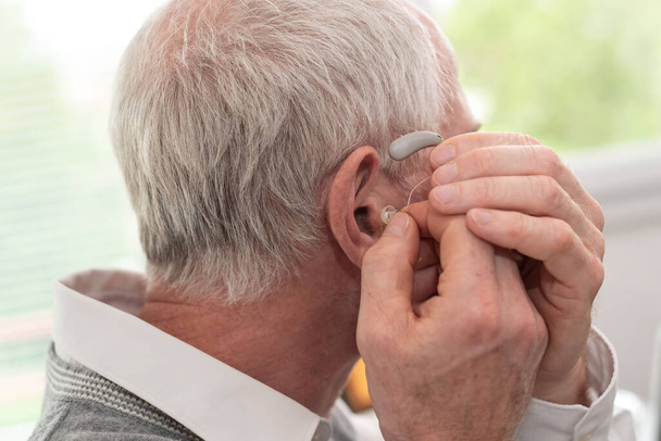 Ανώτερος άνθρωπος βάζοντας βοηθήματα ακοής - Φωτογραφία, εικόνα